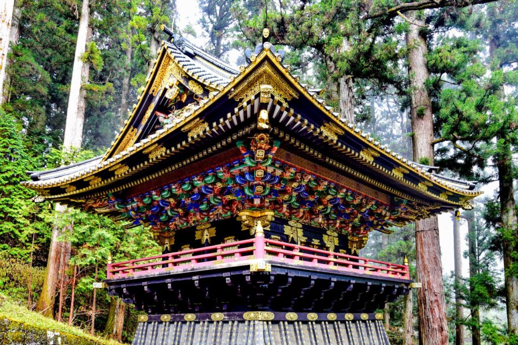 A beautifully ornate Japanese temple amongst towering trees in Nikko, Japan.