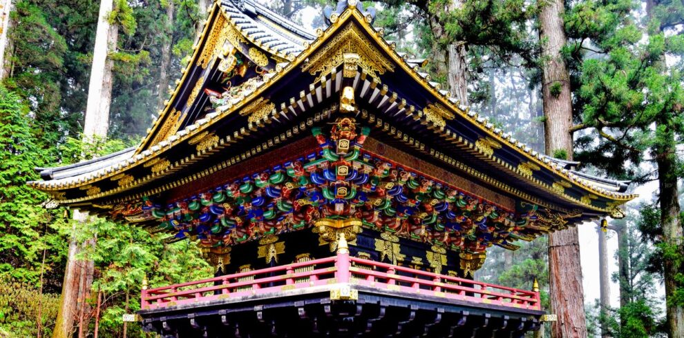 A beautifully ornate Japanese temple amongst towering trees in Nikko, Japan.
