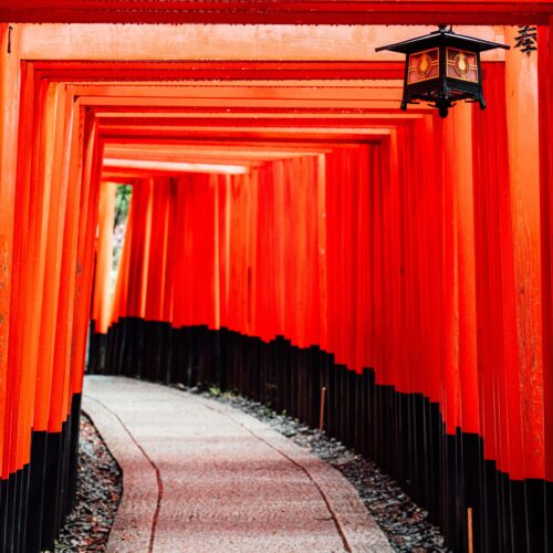 Explore the iconic red torii gates of Fushimi Inari Shrine in Kyoto, Japan, featuring traditional architecture.