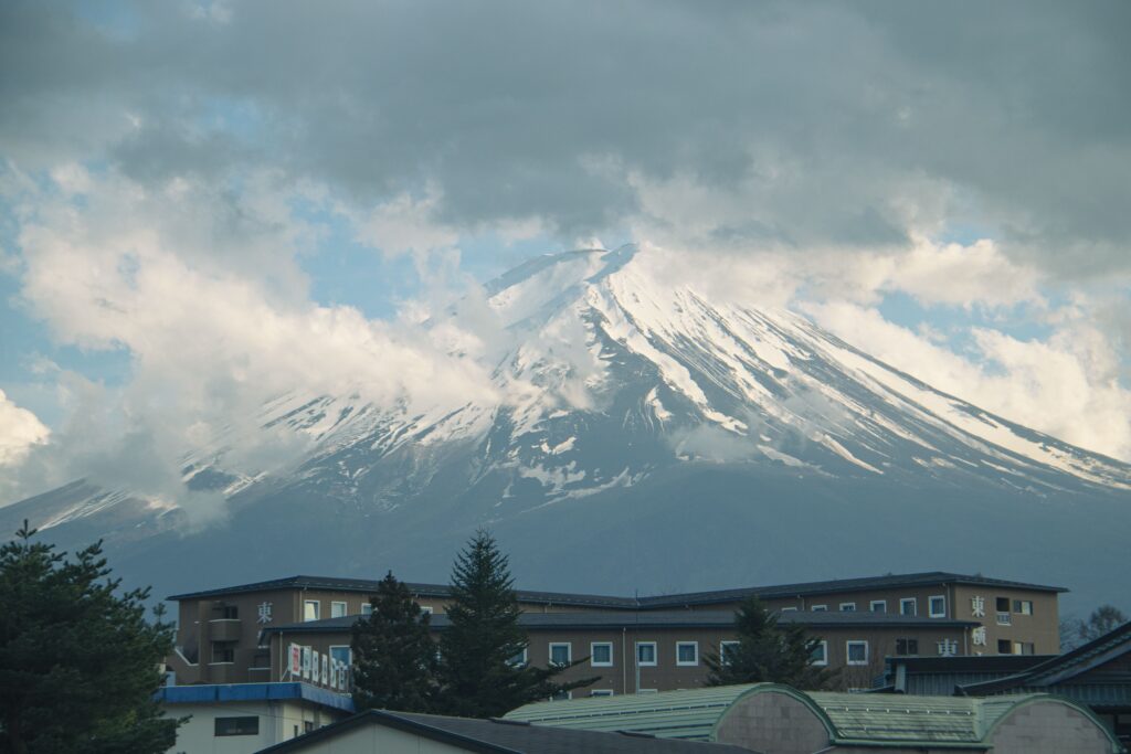 Breathtaking view of Mount Fuji partially covered by clouds above a building.