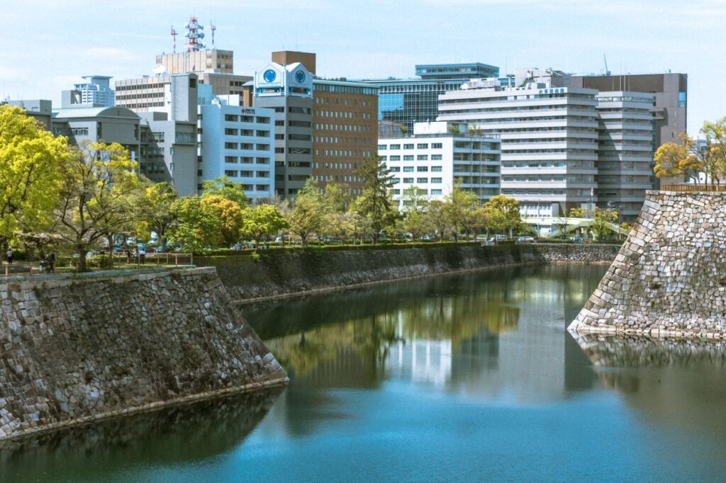 Trip Search Result City skyline reflected in a moat surrounded by greenery. Featured in the modern Japanese cityscape.