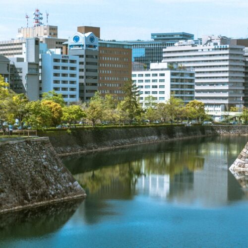 City skyline reflected in a moat surrounded by greenery. Featured in the modern Japanese cityscape.