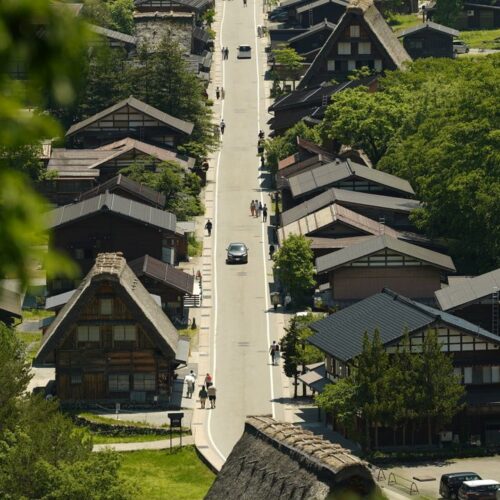 Aerial view of Shirakawa village featuring traditional Gassho-Zukuri farmhouses surrounded by lush greenery.
