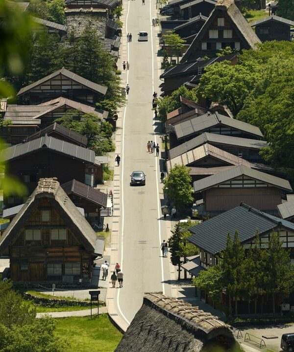 Aerial view of Shirakawa village featuring traditional Gassho-Zukuri farmhouses surrounded by lush greenery.