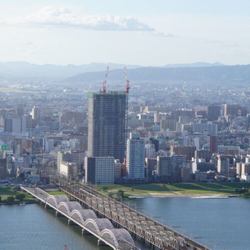Stunning aerial view of Osaka cityscape featuring bridges over a river under a clear blue sky.