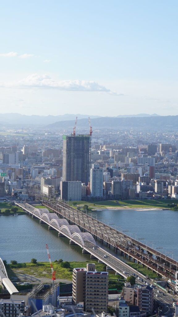 Trip Search Result Stunning aerial view of Osaka cityscape featuring bridges over a river under a clear blue sky.