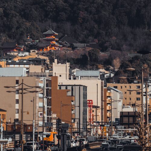 A vibrant view of Kyoto streets with Kiyomizu-dera temple nestled in lush hills.