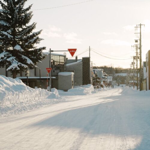 A serene winter street view with snow-covered surroundings in Hokkaido, Japan.