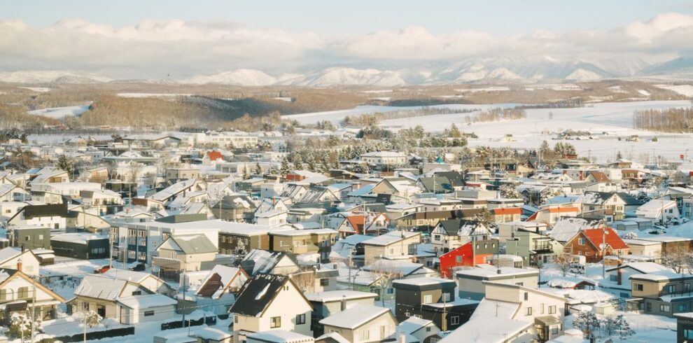 Aerial view of a snow-covered village in Hokkaido, Japan, showcasing scenic winter landscapes.