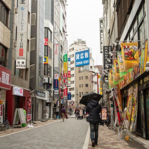 Vibrant Tokyo street scene with pedestrians, neon signs, and urban atmosphere.
