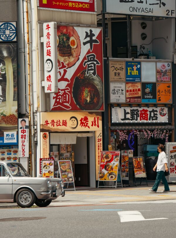 Vibrant Tokyo street scene featuring shopfronts, signs, and pedestrians.