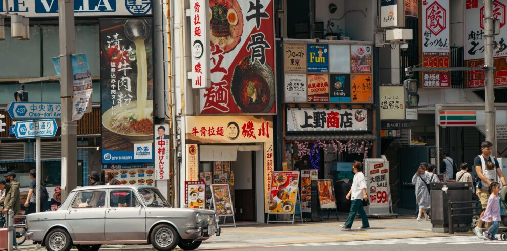 Vibrant Tokyo street scene featuring shopfronts, signs, and pedestrians.