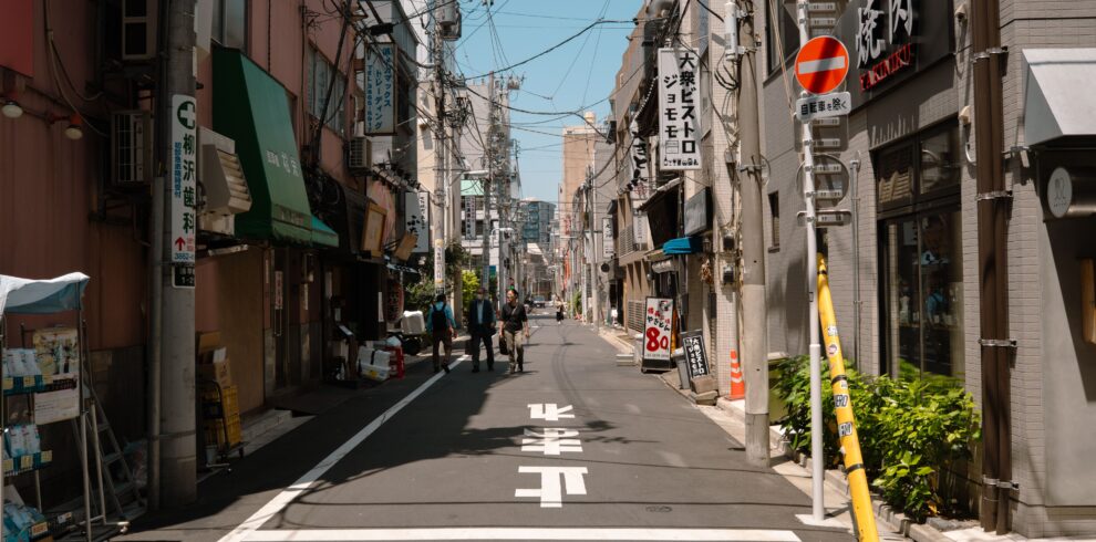 A quiet street in Tokyo, showcasing urban life and traditional architecture on a sunny day.