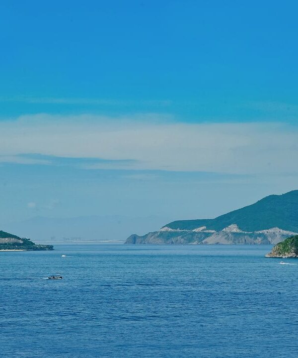 A vibrant and tranquil coastal view showcasing distant islands under a clear blue sky.