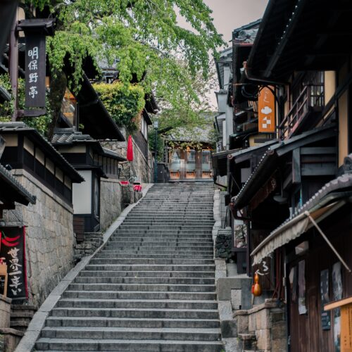 Charming historic street in Kyoto featuring traditional wooden buildings and a stone staircase.