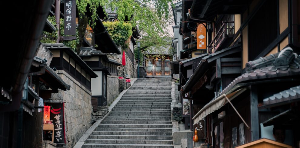 Charming historic street in Kyoto featuring traditional wooden buildings and a stone staircase.