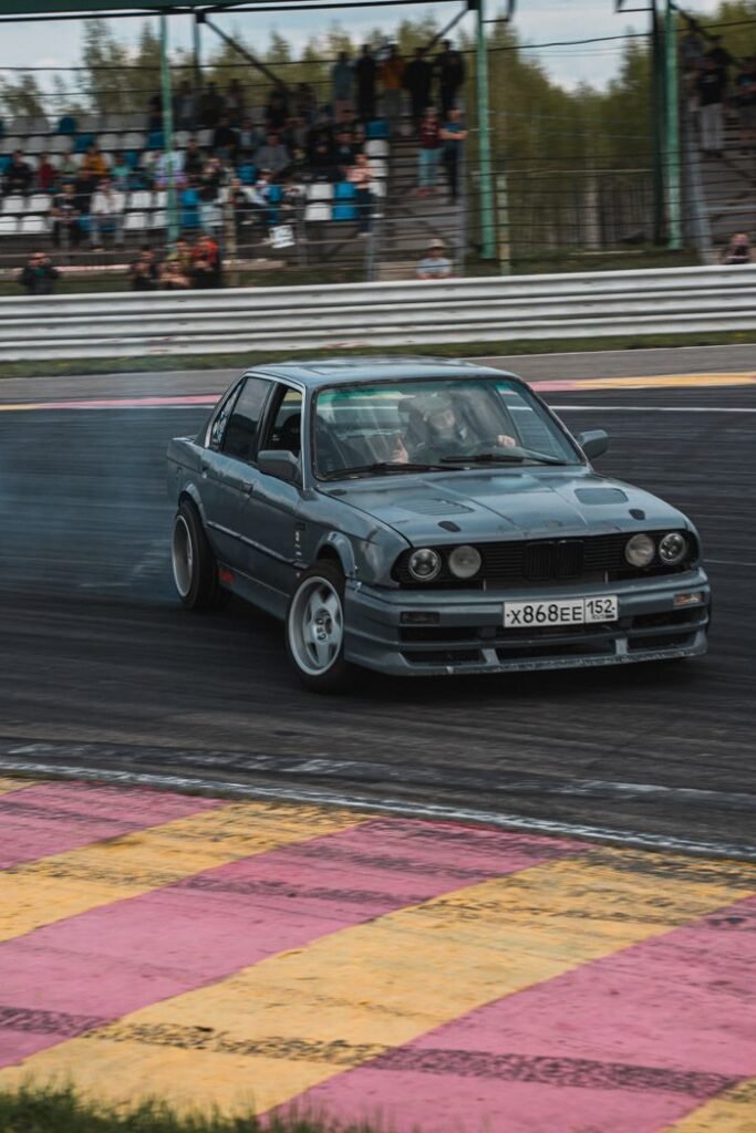 A classic BMW E30 car in action drifting on a race track.