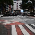 View of bustling Shibuya Crossing in Tokyo with vibrant city lights and busy traffic.