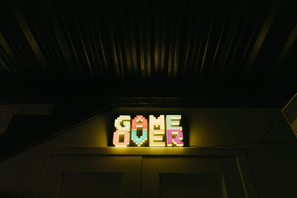Glowing neon sign with pixelated Game Over text in a dark arcade setting.
