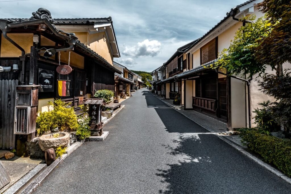 Explore a serene traditional Japanese street lined with historic wooden houses under a clear blue sky.