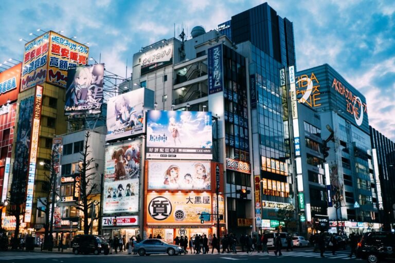 Low angle exteriors of contemporary buildings with colorful signs and monitors located in Tokyo downtown against cloudy blue sky